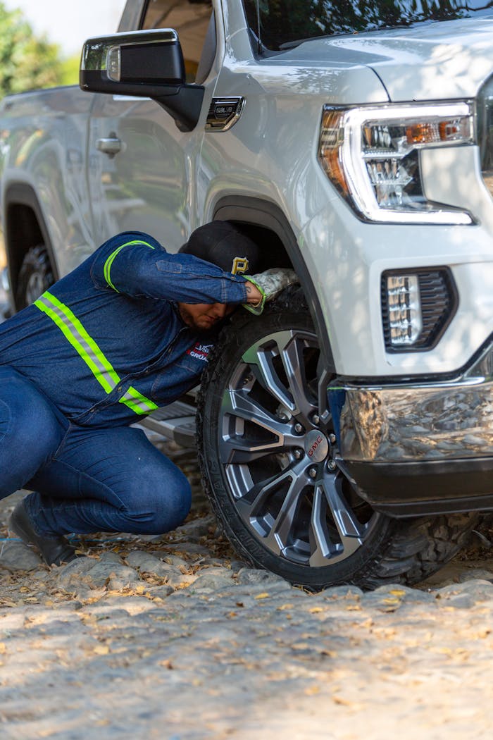 hero-gallery-02 Mechanic working on the wheel of a white off-road vehicle outdoors, fixing a problem.